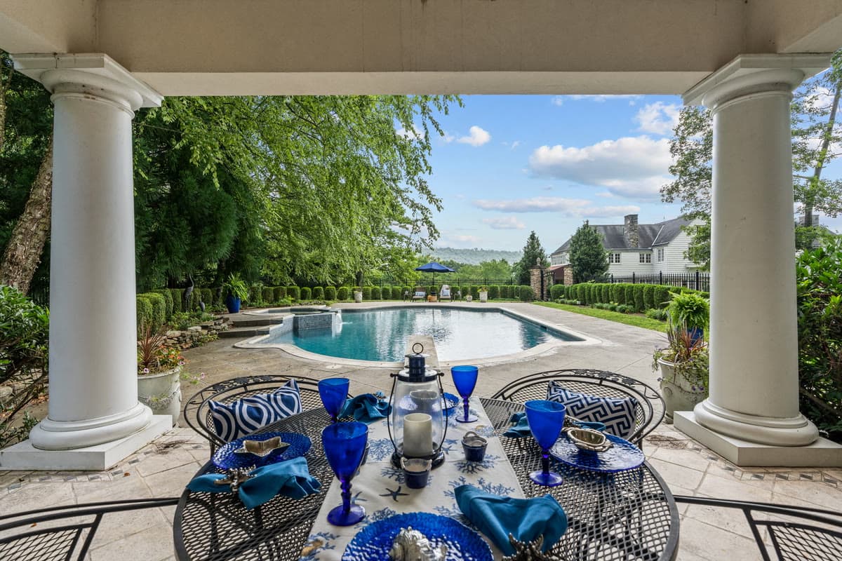 A columned loggia set for lunch, looking out over a pool and open countryside