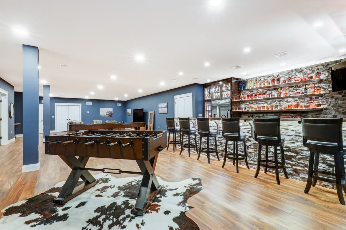 A lower level game room with a foosball table, a cowhide rug, and bar seating