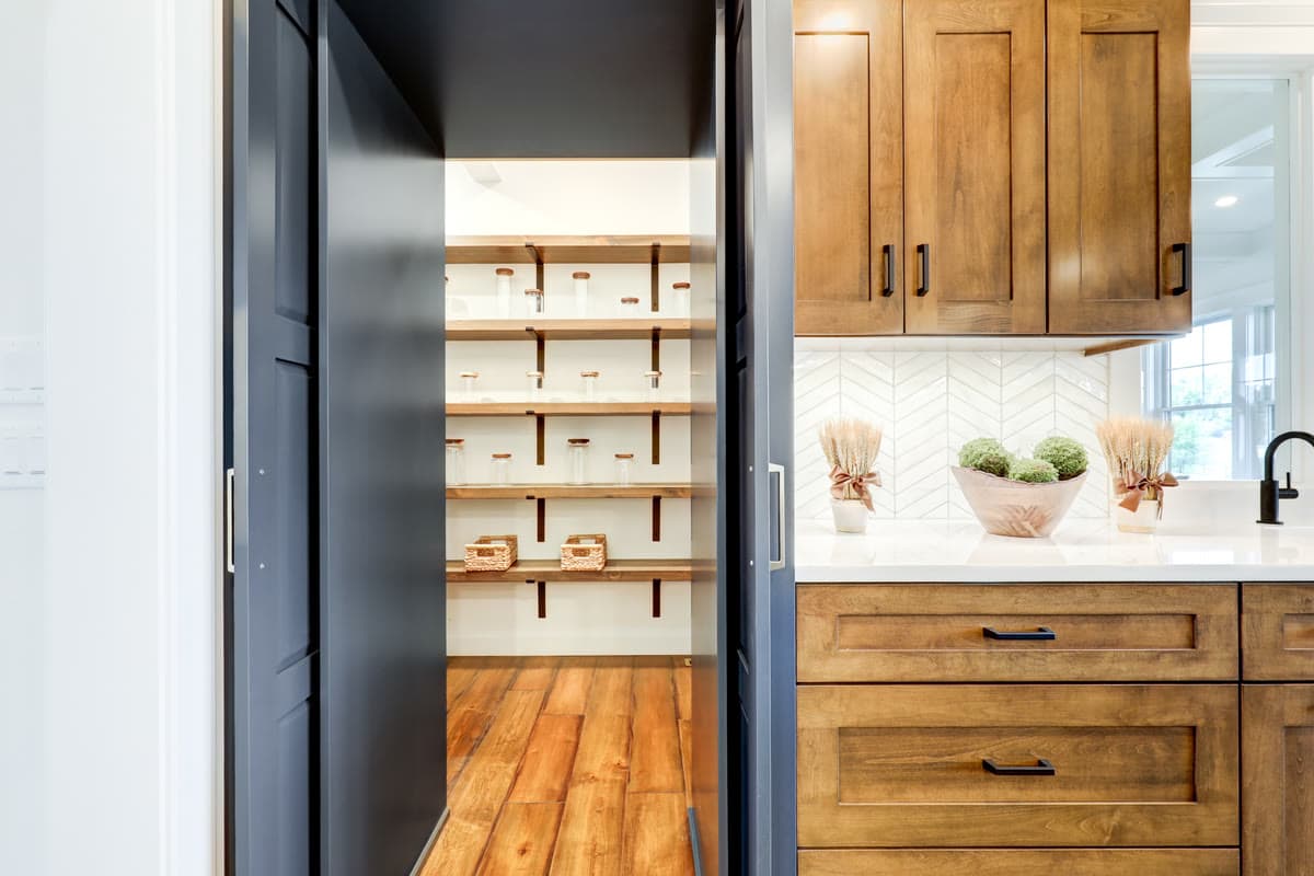 A walk in pantry with open shelving behind a navy door