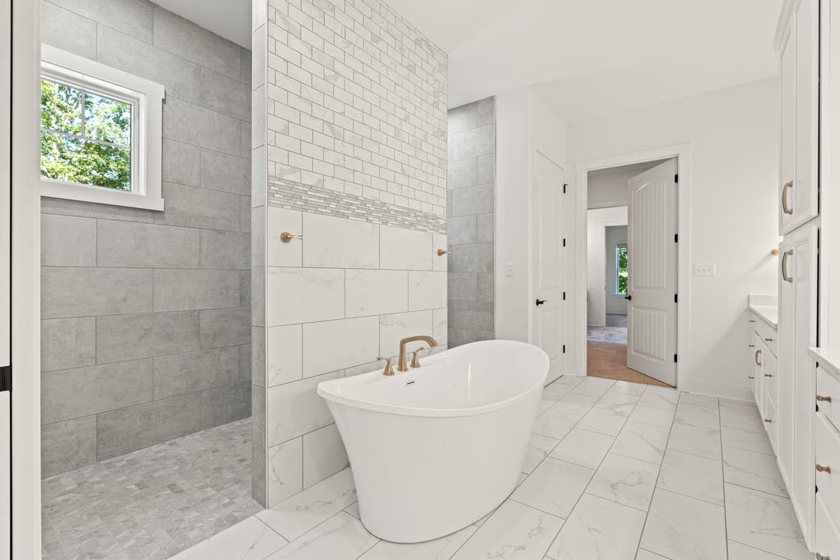 A primary bath with a freestanding tub beside an open tiled shower