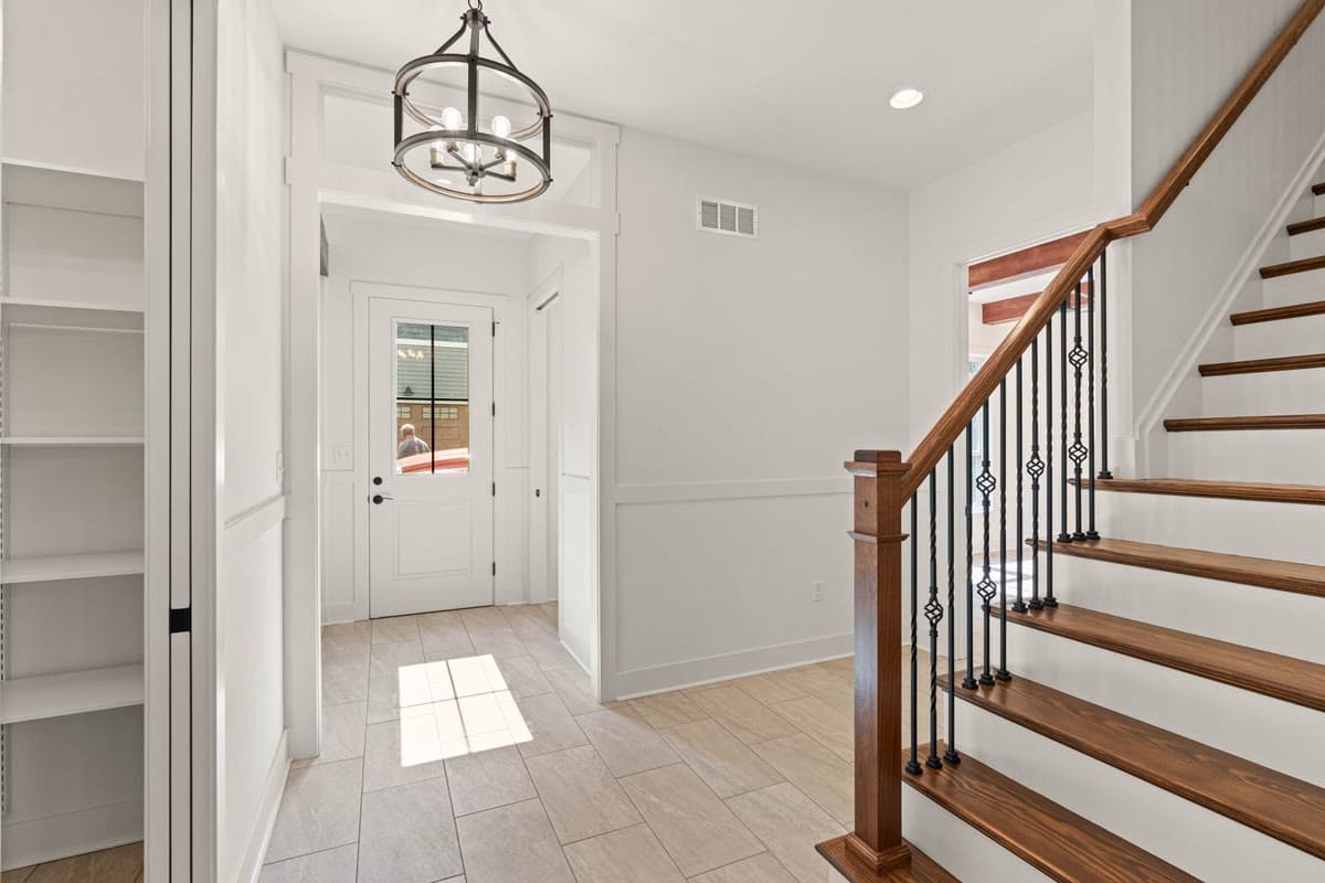 An entry hall with a lantern pendant and a staircase with iron balusters